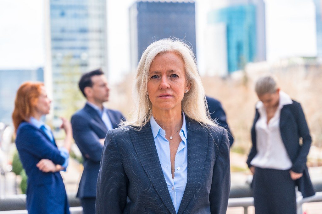 Frau im Business-Kontext, fokussiert, Team im Hintergrund