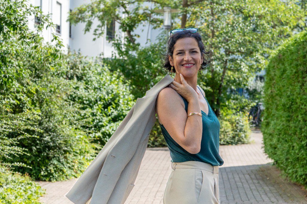 Katja Hainz im Freien, lächelnd, Blazer über der Schulter