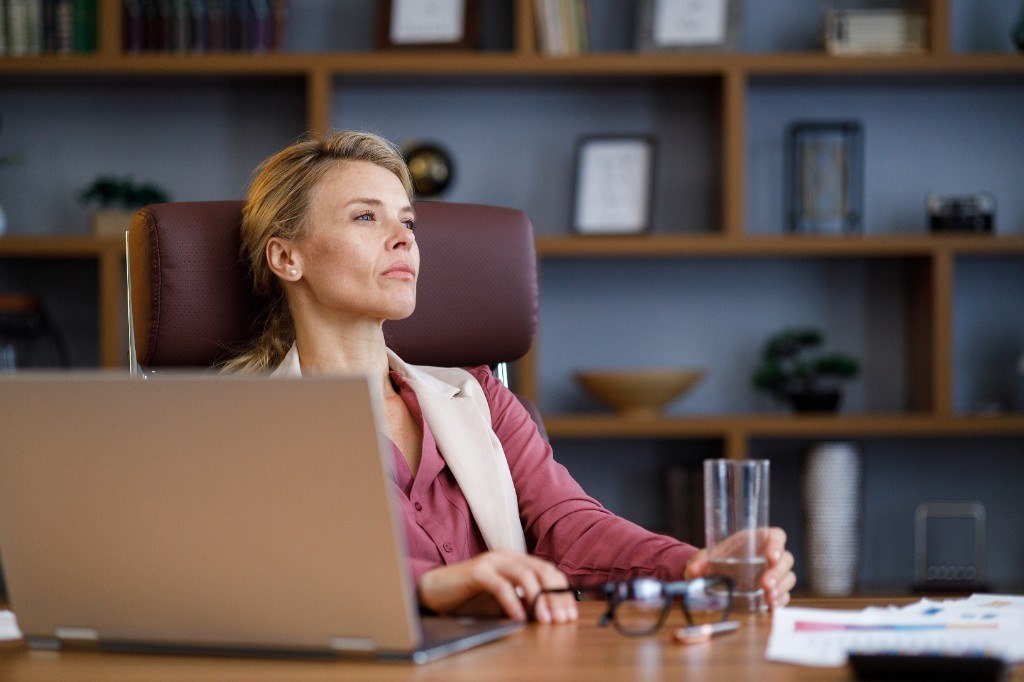 Frau am Schreibtisch im Büro, nachdenklich, Blick nach rechts